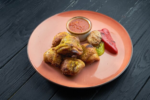 An appetizing Turkish dish - chicken thigh kebab with grilled vegetables and red, served in a red plate