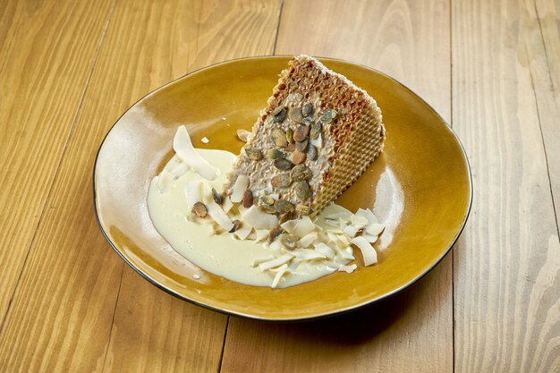 Appetizing waffle cake with condensed milk, custard and coconut chips. Delicious dessert. Wood background