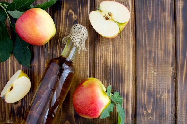 Apple azijn cider in de glazen fles op de bruine houten oppervlak.