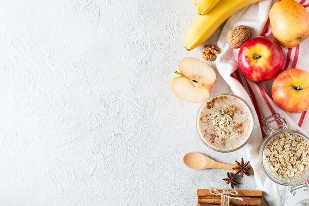 Mela e banana frullato di farina d'avena prima colazione salutare su sfondo di pentecoste