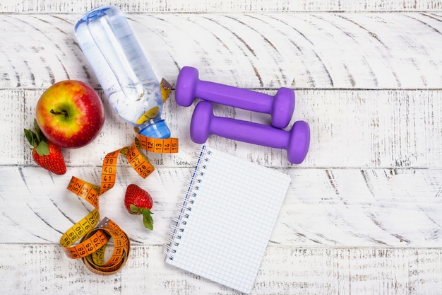 Apple, bottle of water and measuring tape on white