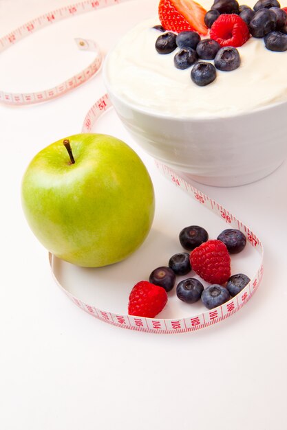 Apple and bowl of berries cream and a tape measure 