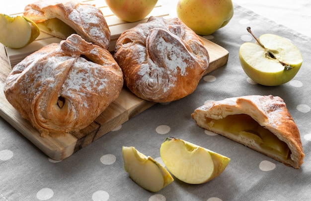 Photo apple buns with powdered sugar and apples on the wooden board
