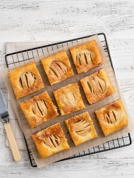 Apple cake sliced in square portions on white wooden table Fall pie autumn bakery