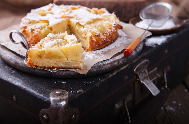 Apple cake on a vintage suitcase in powdered sugar.