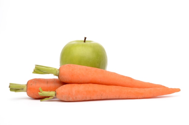 Apple and carrots on a white surface