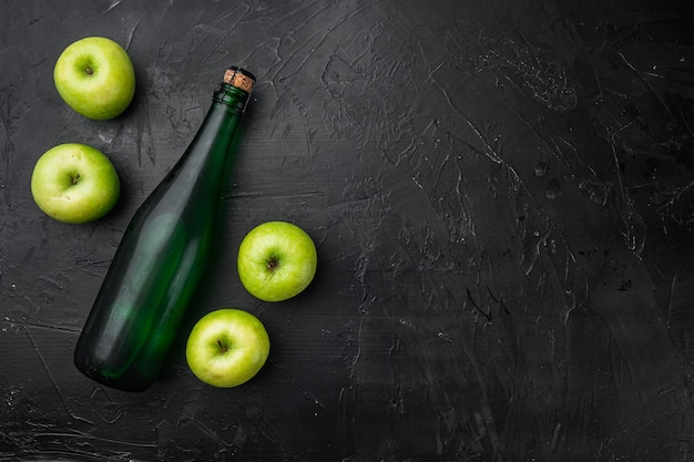 Apple cider bottle set, on black dark stone table background, top view flat lay, with copy space for text