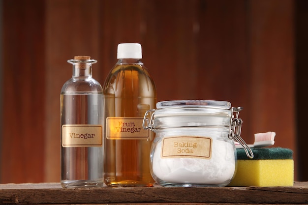 Apple cider vinegar baking soda and cleaning sponge on wooden background