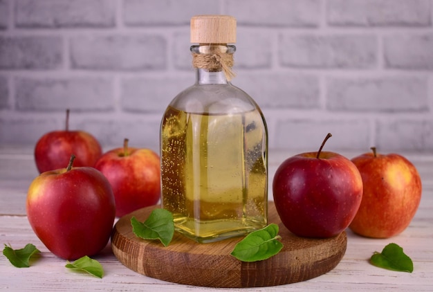 Apple cider vinegar and fresh apple on a wooden background