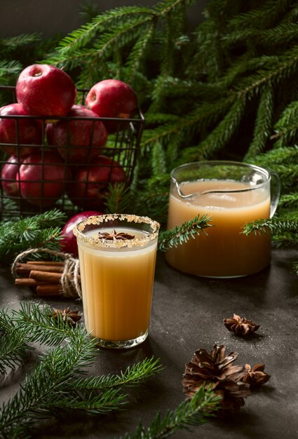 Apple-cidercocktail met kardemom en steranijs op zwarte lijst met sparrentakken.