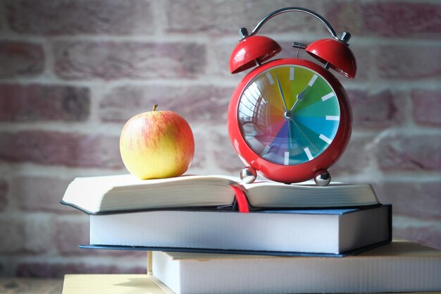 Foto mela e orologio su pila di scuola di sfondo libro