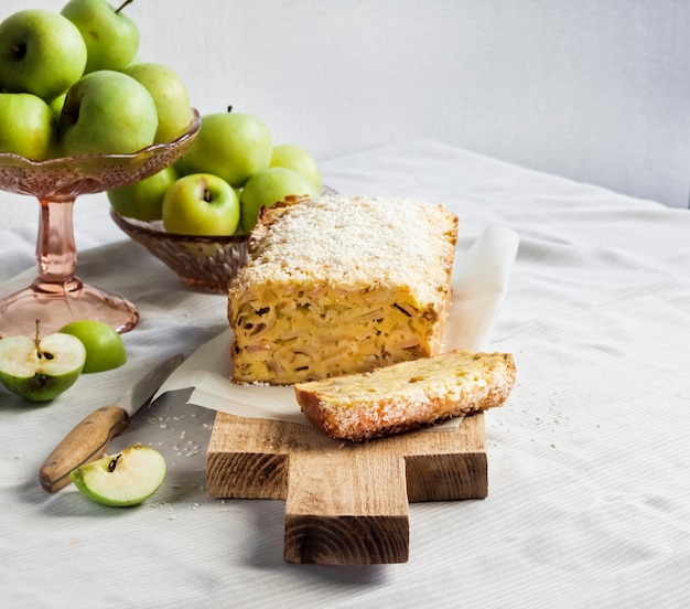 Apple and coconut loaf cake and apples in a vase on a table. Copy space