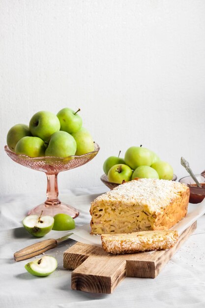 Apple and coconut loaf cake and apples in a vase on a table. Copy space