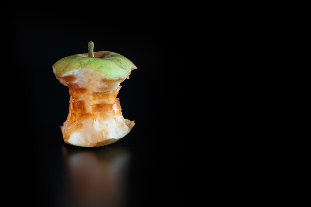 Apple core on a black background with reflexion. Ecology and garbage recycling concept.