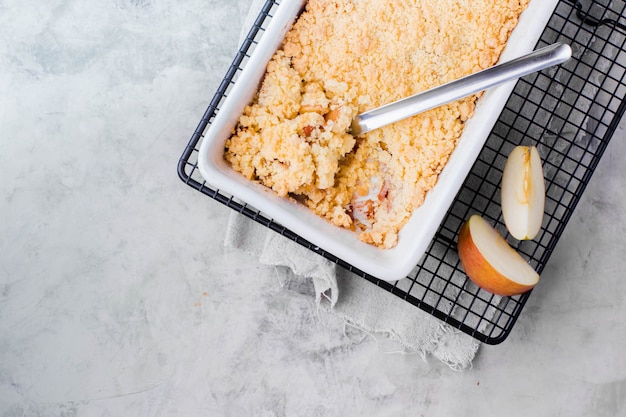 Apple crumble in white ceramic form on gray table background. 