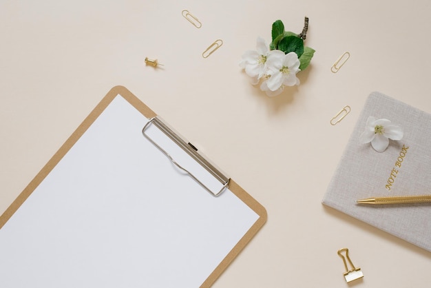 Notebook e tablet con fiori di mela con mockup di carta su un tavolo beige desktop floreale femminile