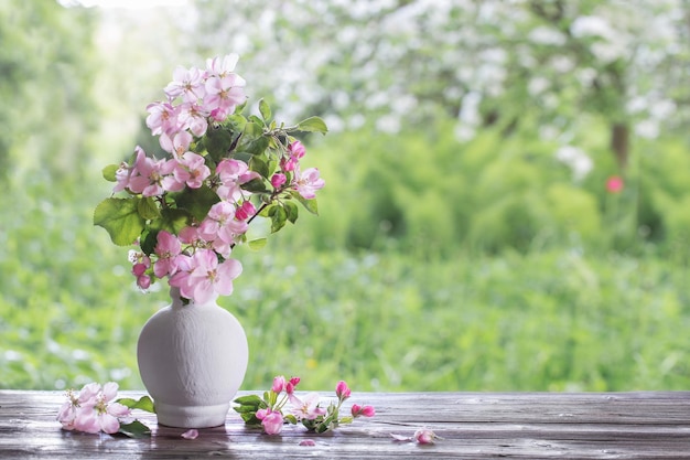 Apple flowers in white vase on background spring garden