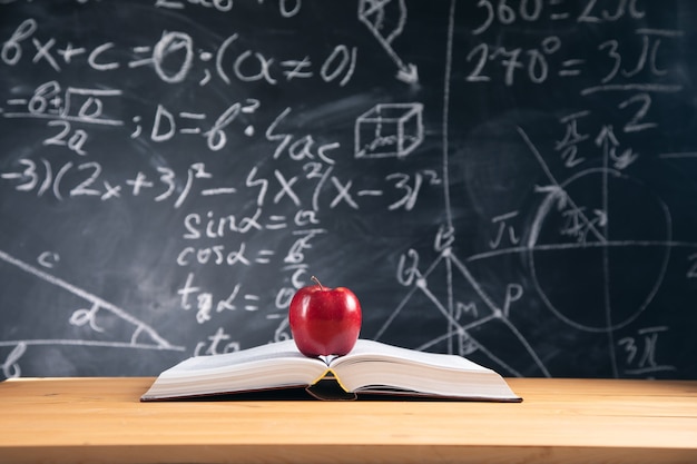 The apple fruit on book with blackborad background