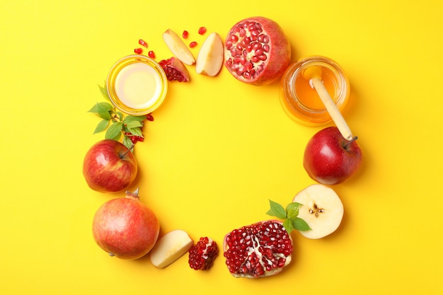 Apple, honey and pomegranate on yellow, space for text