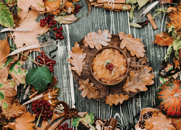 Apple jam and autumn leaves on old wooden table background