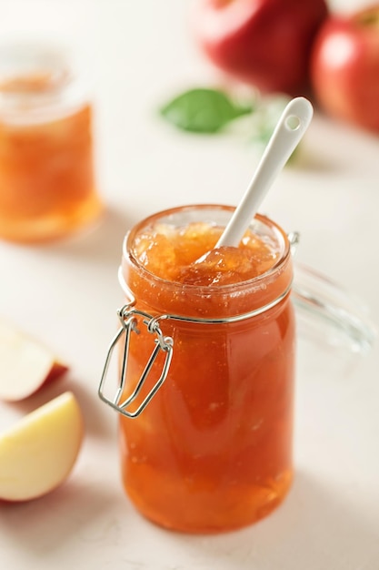 Apple jam in a glass jar. Apple jam on a light background. Delicious natural marmalade.