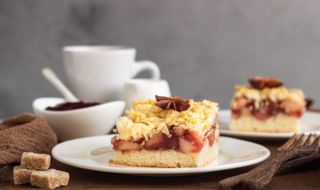 Apple, jam and spices crumble topping cake on wooden tray.