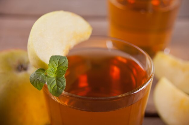 Apple juice and apples on wooden table. 