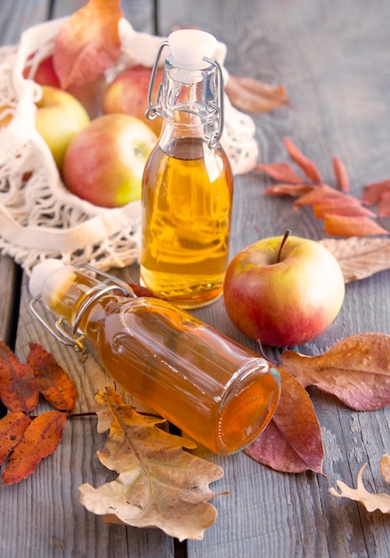 Apple juice in bottles and apples in a grid on a wooden\
background