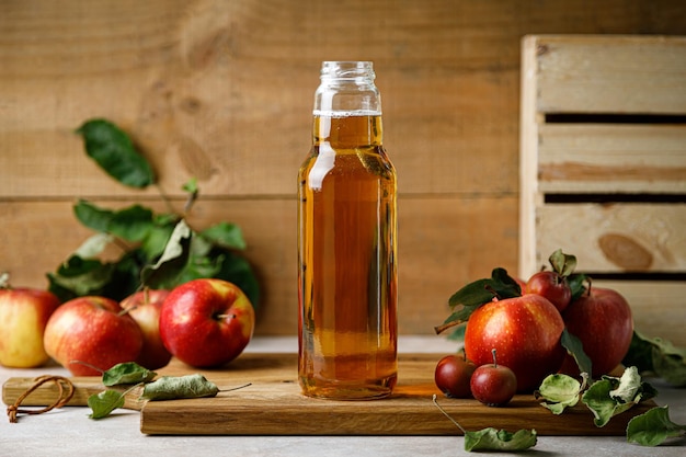 Apple juice in a glass bottle and fresh fruits with leaves