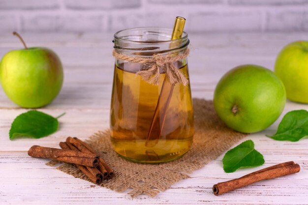 Apple juice in a jar and fresh green apples with cinnamon sticks