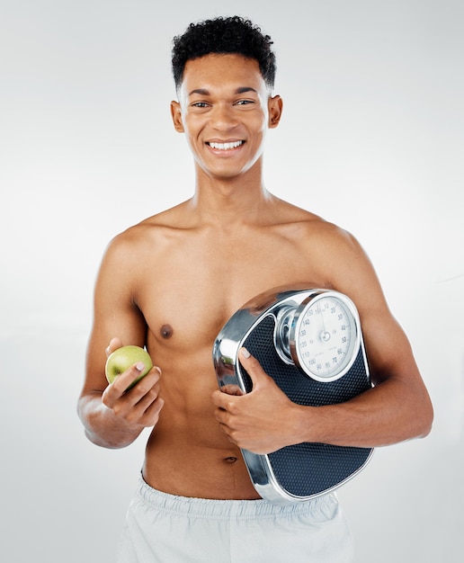 Apple man and scale for health fitness and diet in studio against white background mockup for weight loss Fruit training and wellness model with black man happy smile and relax with nutrition