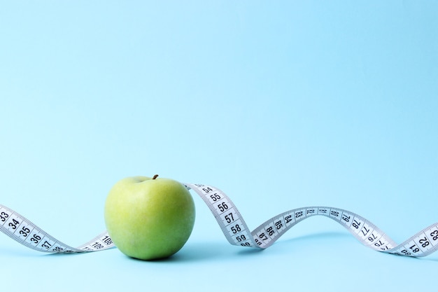 Apple and measuring tape on a colored background closeup with place for text