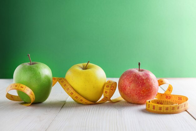 Apple and measuring tape on a green background