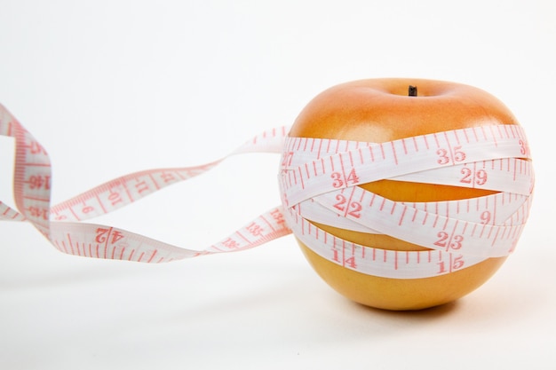 Apple & measuring tape on white background.