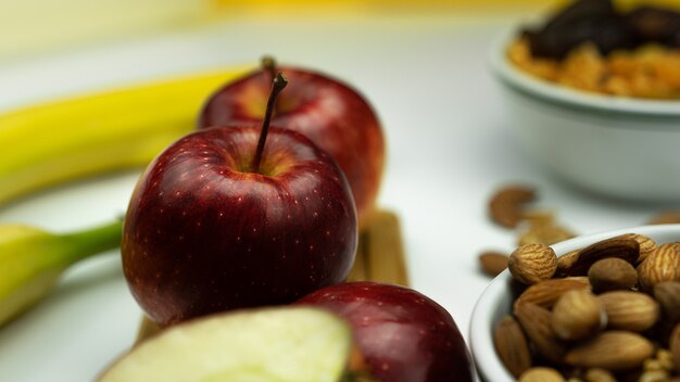 An Apple, nuts, and bananas placed on a white.