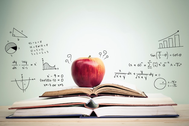 Фото apple на стопку открытых книг с образованием каракулей и копией пространства. концепция образования