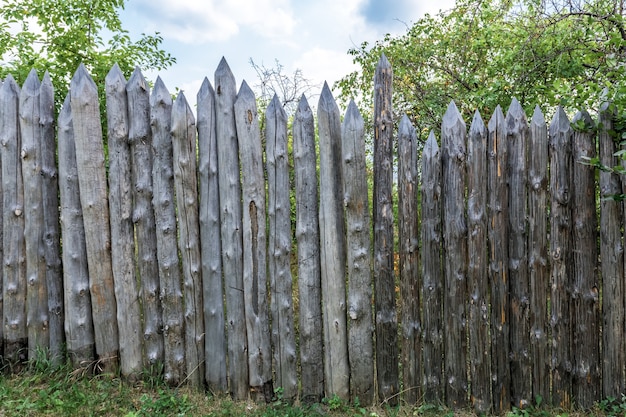 The apple orchard is fenced with a palisade of old weathered logs Antique wooden fence