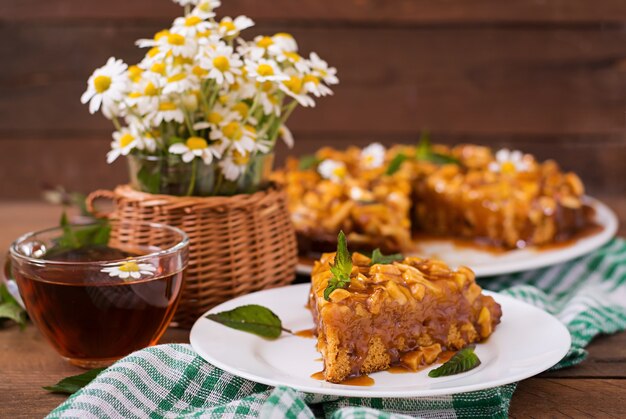 Apple pie with caramel sauce on a wooden background