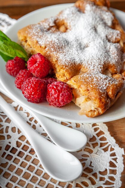 Apple pie with fresh raspberries and mint on a wooden background Selective focus