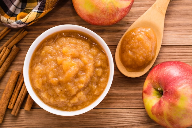 Apple puree, apples and cinnamon on a wooden table, top view