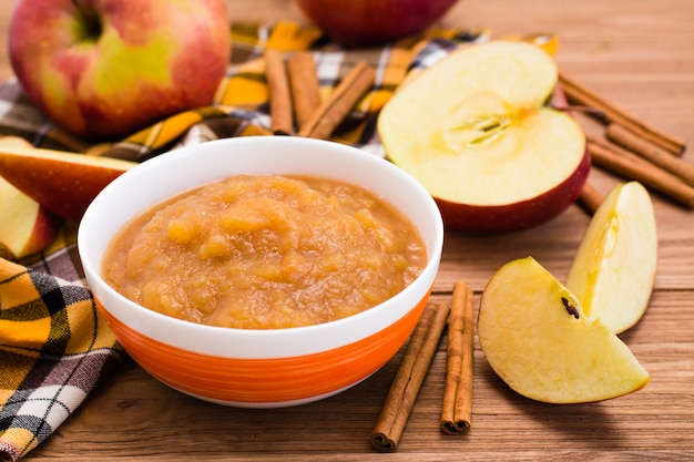 Apple puree, apples and cinnamon on a wooden table