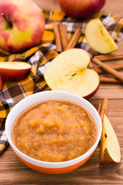 Apple puree, apples and cinnamon on a wooden table