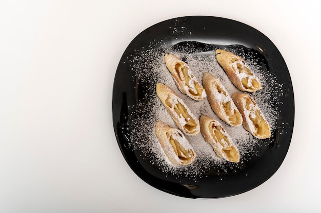 Apple roll, strudel on black plate on white background. Copy space.