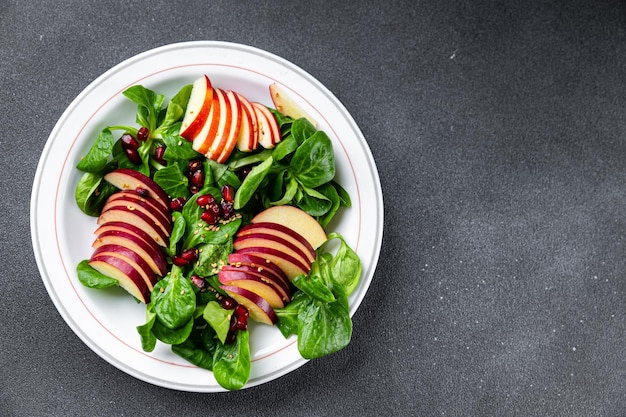 apple salad, green mix lettuce, pomegranate grain healthy meal food snack on the table copy space