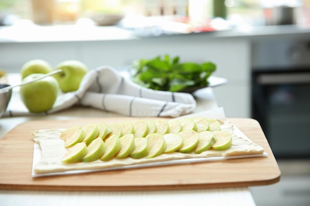 Apple slices on puff dough in kitchen