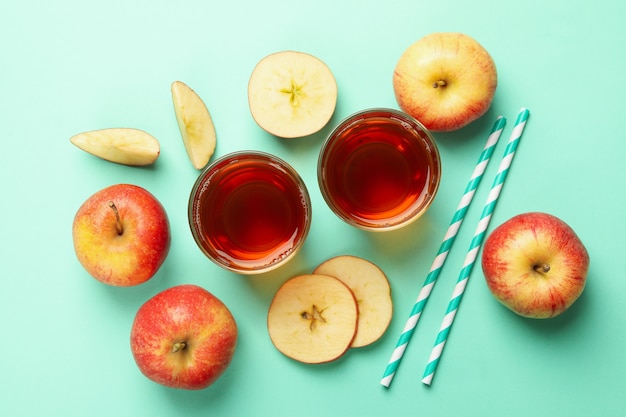 Apple slices, straws and glasses of apple juice on mint