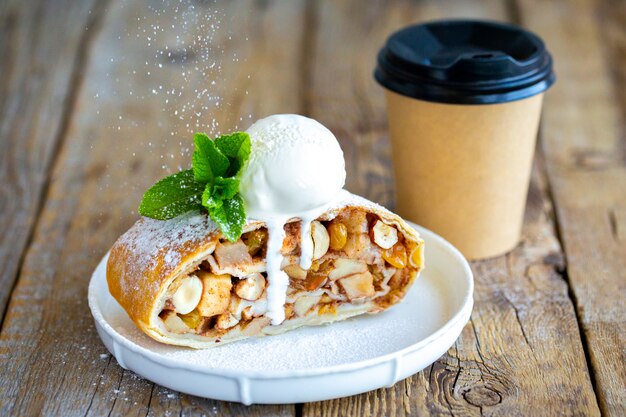 Strudel di mele cosparso di zucchero a velo.un pezzo di strudel di mele su un tavolo di legno.