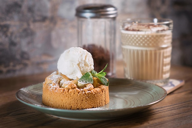 apple strudel with ice cream and mint on the plate and white creamy cocktail on the table