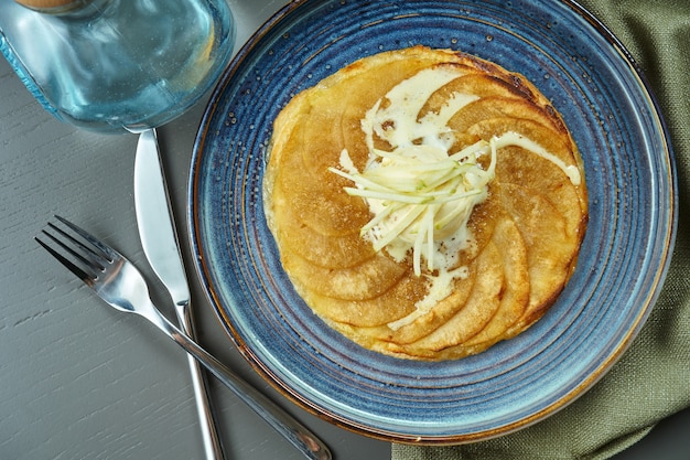 Apple strudel with vanilla ice cream on a blue plate on a wooden table. Popular Austrian pastries and dessert. Top view, flat lay with copy space