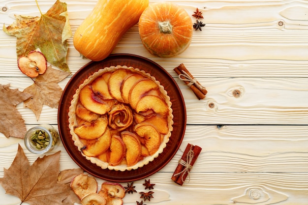 Apple tart pie on table decorated with pumpkin and dry leaves